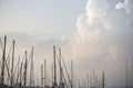 Yachts masts tops under Larnaca` s blue sky with fluffy clouds. Sky and town background.