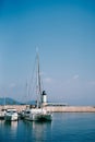 Yachts and a sailing catamaran moored near a breakwater with a lighthouse. Lustica Bay, Montenegro
