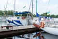 yachtsman goes from boat on pier. Young man moored his yacht in river dock. Male hobbies and lifestyle.