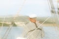 Yachtsman in marine clothing looking into the distance sitting on board a sailing yacht. Sea fishing from the ship. Peaceful state Royalty Free Stock Photo