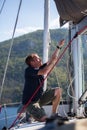 Yachtsman pulls the rope on the mast, on his sailing yaht boat