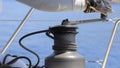 Yachtsman rotates the halyard winch with yacht ropes