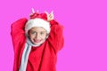 7 yaers old smiling girl with changing tees smiling in santa hat, red pullover, gray scarf, imitation of christmas dear with smile Royalty Free Stock Photo