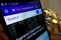 Yahoo website displayed on Samsung smartphone and stack of coins