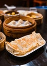 Yaki-Gyoza set Japanese Pan-Fried Dumplings served on a white plate with Xiao Long Bao in a bamboo steamer in the background