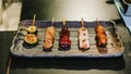 Yakitori Japanese-Style Grilled Chicken Skewers with chicken, internal organ and cucumber served on black stone plate Royalty Free Stock Photo