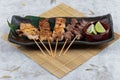 Yakitori Japanese-Style Grilled Chicken Skewers with chicken and internal organ served with sliced lime on black stone plate. Royalty Free Stock Photo