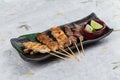 Yakitori Japanese-Style Grilled Chicken Skewers with chicken and internal organ served with sliced lime on black stone. Royalty Free Stock Photo