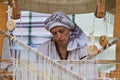 Portrait of woman weaver working at ancient loom, making carpet