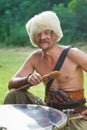 Portrait of Zaporozhian Sich cossack, kozak characternik sitting at a kettledrum, holding drum sticks and smiling