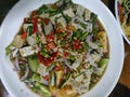 Yam Mu Yor is spicy boiled pork salad along with fresh herbs, vegetables, and a spicy and tangy dressing on white dish Royalty Free Stock Photo