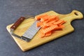 Yams, sweet potato cut in pieces with a special knife with ribs on a cutting board on a grey background. Cooking step by