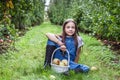 yang girl with basket full of ripe apples in a garden or farm near trees