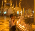 A man praying beside some candles at the Shwedagon Pago in Yangon, Myanmar