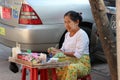 Myanmese female street vendor selling betel quids, it is a areca nuts, lime and tobacco wrapped in a betel leaf for chew, beside Royalty Free Stock Photo