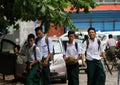 Four collegians in Myanmarese uniform of college white shirt and green Long Yi walking homing on the street after school program