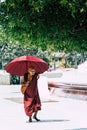 Yangon, Myanmar - March 2019: old Buddhist monk with red umbrella walks in Shwedagon pagoda