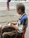 Yangon, Myanmar - November 3, 2019: Manpreparing betel leaf for chewing tobacco in the streets