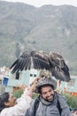 YANQUE, COLCA VALLEY, PERU - JANUARY 20, 2018: Native woman puts an eagle in a tourist`s head in Yanque, Peru