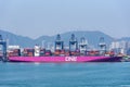 Large pink container ship berthed in the container terminal.