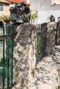 A yard around the house with concrete posts with stones at the ends