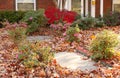 Yard of pretty house that needs yardwork - fall leaves in flowers and on sidewalk Royalty Free Stock Photo