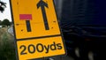 200 yards roadworks warning sign on UK motorway at evening with traffic passing Royalty Free Stock Photo