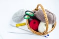 Yarn for knitting natural tones and accessories for needlework in a basket on a white background. Balls, knitting needles, centime