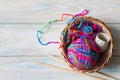 Yarn of rainbow colors and knitting needles on light wooden background