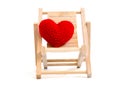 Yarn red heart on the wooden beach chair on white background is