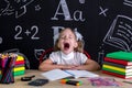 Yawning girl sitting at the desk with books, school supplies