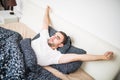 Yawning and stretching man waking in bed at home