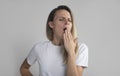 Yawning tired bored woman. Beautiful caucasian model isolated on grey studio background