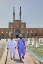 Islamic clergymen stroll near mosque on sunny day, Yazd, Iran.