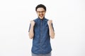 Yeah boy we did it. Thrilled happy and delighted good-looking young male in beanie and glasses yelling yes raising Royalty Free Stock Photo