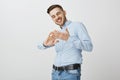 Yeah I am billionaire. Delighted stylish and successful young businessman in blue shirt with cool haircut smiling Royalty Free Stock Photo