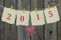 Year 2015 on antique paper with red fabric heart hanging on clothesline by wood fence Royalty Free Stock Photo