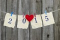 Year 2015 on antique paper with red heart hanging on clothesline by shabby wood fence Royalty Free Stock Photo