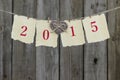 Year 2015 on antique paper with wooden heart hanging on clothesline by wood fence Royalty Free Stock Photo