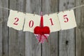 Year 2015 on antique parchment paper hanging on clothesline with red heart by wooden background Royalty Free Stock Photo