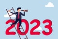 Year 2023 business outlook, vision to see the way businessman leader using telescope to see vision on top of ladder above year