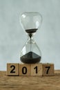 Year end 2017 business time countdown or improvement review concept as hourglass or sandglass with wooden cube block number 2017 Royalty Free Stock Photo