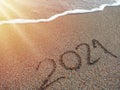 Year 2021 hand written on sandy beach in sunset warm lens flare Royalty Free Stock Photo