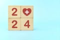 Year 2024 health goal and healthcare priority concept. Wooden blocks on blue background with icon.