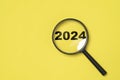 2024 year inside of magnifier glass on yellow background for focus and preparation new year change and start new business target Royalty Free Stock Photo