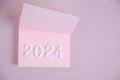 Year 2024 is laid out in white numbers pink sheet.Concept time and new year