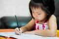 A 3-4 year old Asian child girl is doing her homework. Kid hold black crayons to paint in their workbooks. Children learn at home Royalty Free Stock Photo