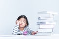Asian girl, looking at the stack of books stacked on white table With boredom Royalty Free Stock Photo