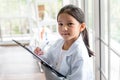 A 6 year old Asian girl wearing a white scientist uniform Learning And make notes
