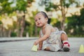 A 1 year old baby boy is learning to walk, child falls and sits on the pavement, a toddler takes his first joyful steps. Royalty Free Stock Photo